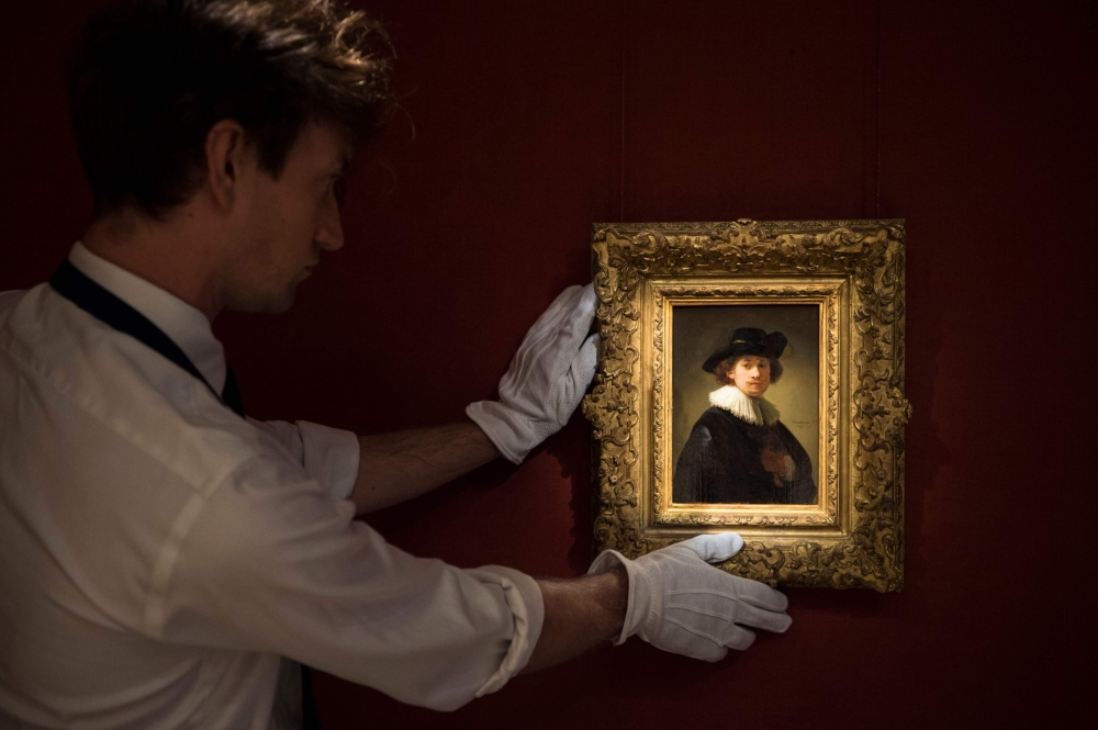 A handout picture released by Sothebys on July 28, 2020 shows an assistant holding a self-portrait by Dutch artist Rembrandt in London. One of the last self-portraits by Rembrandt still in private hands goes on sale in Britain today, with a guide price of