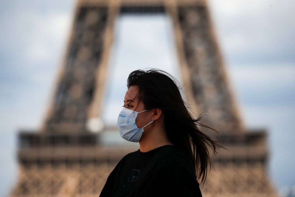 A woman wearing a protective face mask walks at the Trocadero square near the Eiffel Tower in Paris as France reinforces mask-wearing as part of efforts to curb a resurgence of the coronavirus disease (COVID-19) across the country, August 3, 2020. REUTERS