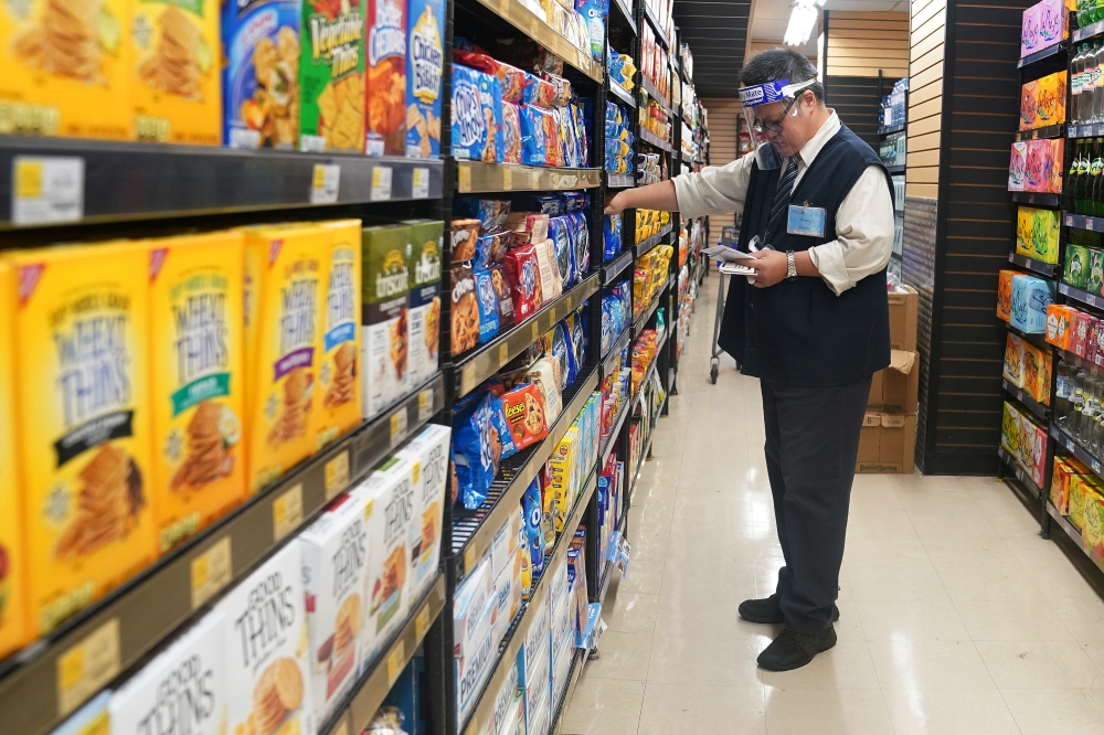 A worker with a face shield checks products on the shelf of a grocery store in the Manhattan borough of New York City, New York, U.S., August 7, 2020. REUTERS/Carlo Allegri