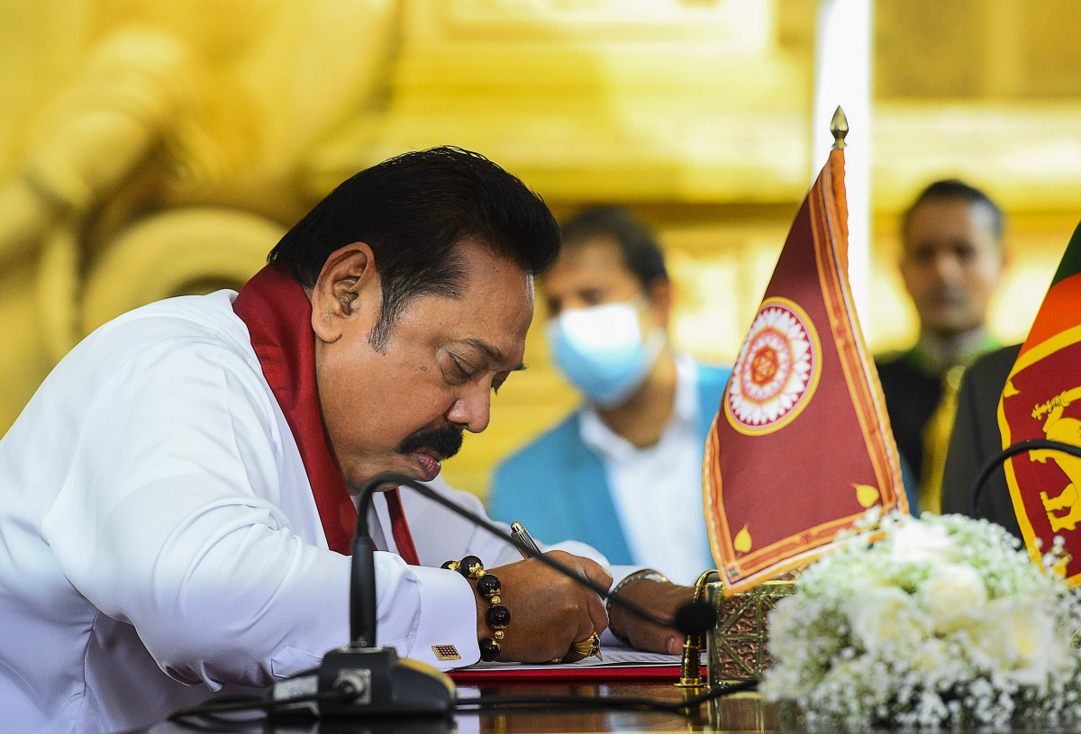 Sri Lanka's Prime Minister Mahinda Rajapaksa signs documents during his swearing-in ceremony at the sacred Kelaniya Raja Maha Buddhist temple, outside the capital Colombo on August 9, 2020.  / AFP / Ishara S. KODIKARA