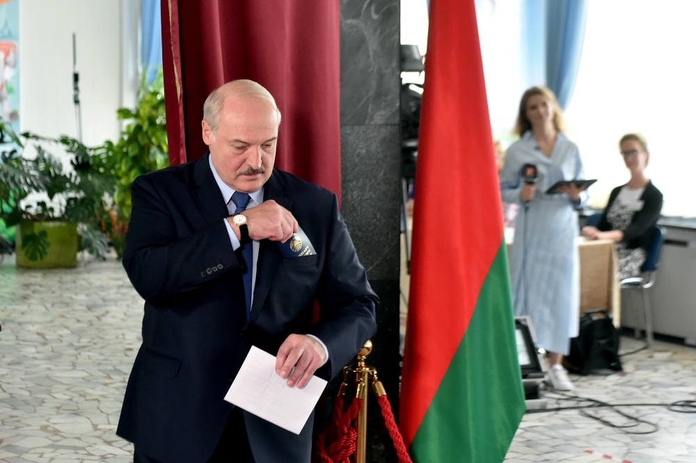 Belarusian President Alexander Lukashenko holds a ballot and a passport before casting his vote at a polling station during the presidential election in Minsk, Belarus August 9, 2020. Sergei Gapon/Pool via REUTERS