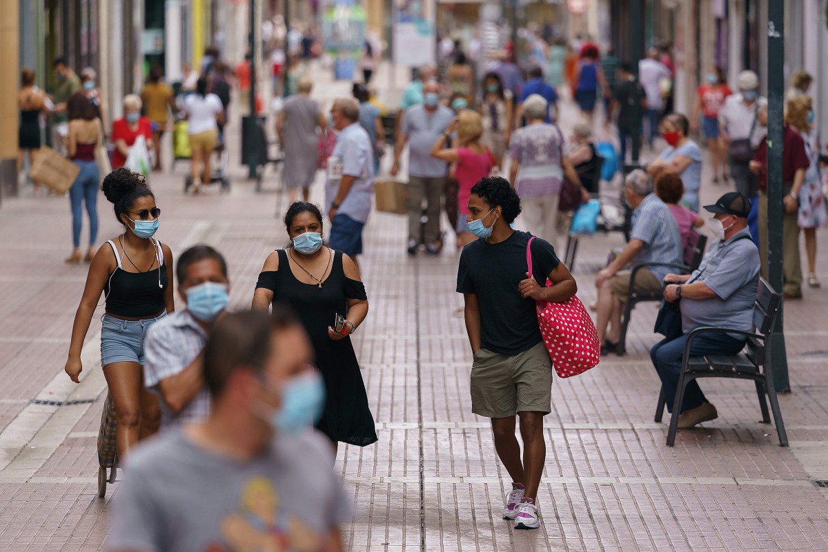 People wearing face masks walk down a shopping street in the Las Delicias neighbourhood of Zaragoza in northeastern Spain on August 10, 2020. Spain has added 19,405 new coronavirus cases in the past week, but the health ministry says the country is not en
