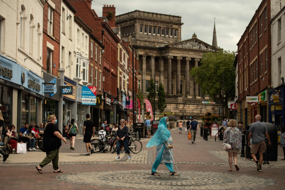 Members of the public walk through the centre of Preston, north west England on August 8, 2020, as local lockdown restrictions are reimposed due to a spike in cases of the novel coronavirus in the city. / AFP / OLI SCARFF