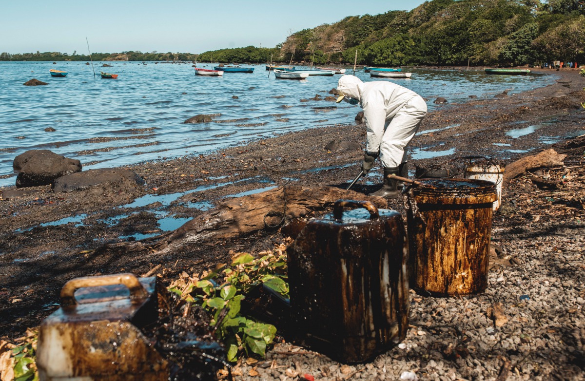 A volunteer cleans oil spilled from the bulk carrier ship MV Wakashio, belonging to a Japanese company but Panamanian-flagged, that ran aground on a reef, at the Mahebourg Waterfront in Riviere des Creoles, Mauritius, August 12, 2020. REUTERS/Stephane Ant