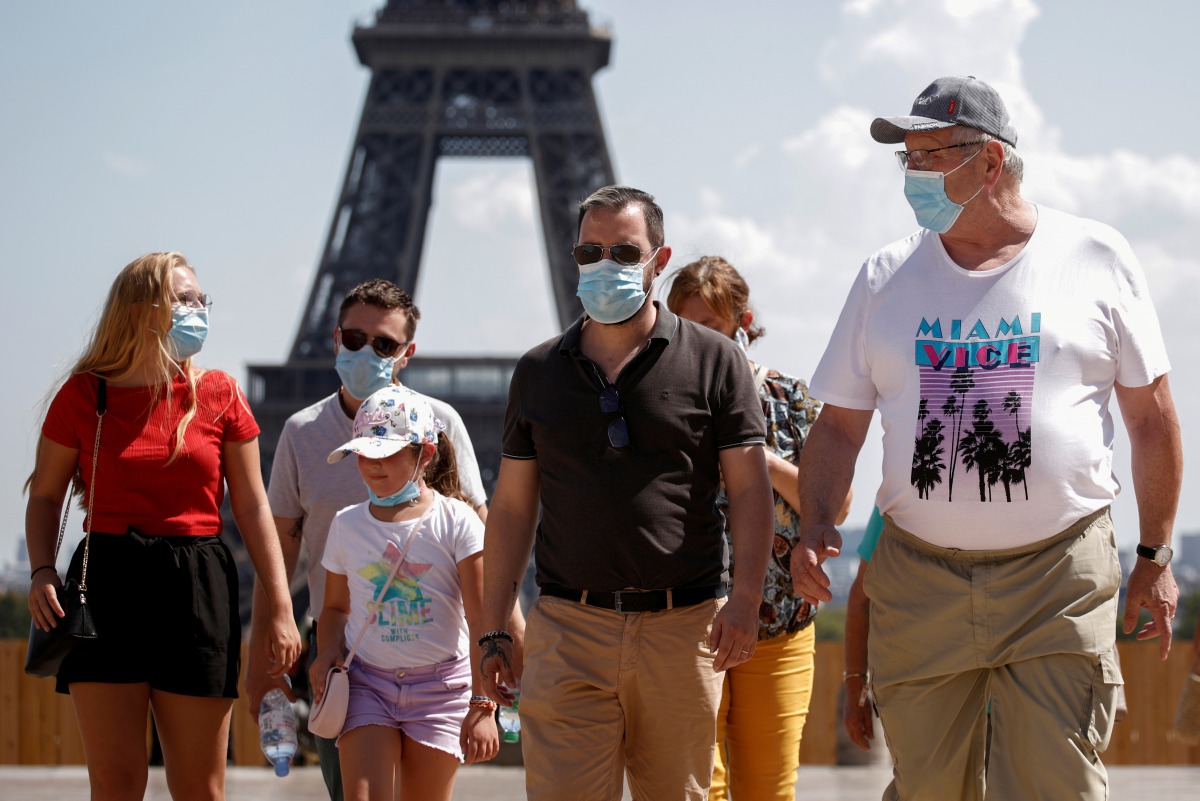 FILE PHOTO: People wearing protective face masks walk at the Trocadero square near the Eiffel Tower in Paris as France reinforces mask-wearing as part of efforts to curb a resurgence of the coronavirus disease (COVID-19) across the country, August 9, 2020