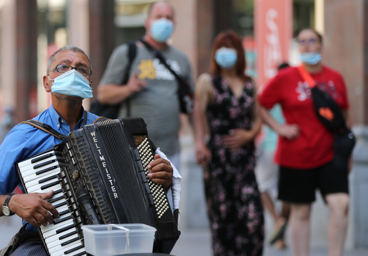 An accordion player wears a protective facemask as he plays on a street in Antwerp on August 6, 2020, as authorities impose additional measures to attempt to curb the spread of the COVID-19 caused by the novel coronavirus