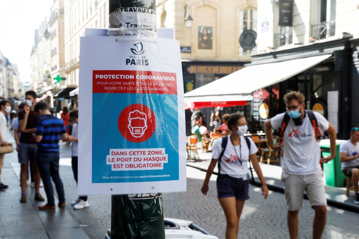 Pedestrians wearing protective face masks walk by a coronavirus disease (COVID-19) information sign, as France reinforces mask-wearing as part of efforts to curb a resurgence of the coronavirus disease (COVID-19) across the country, France, August 13, 202