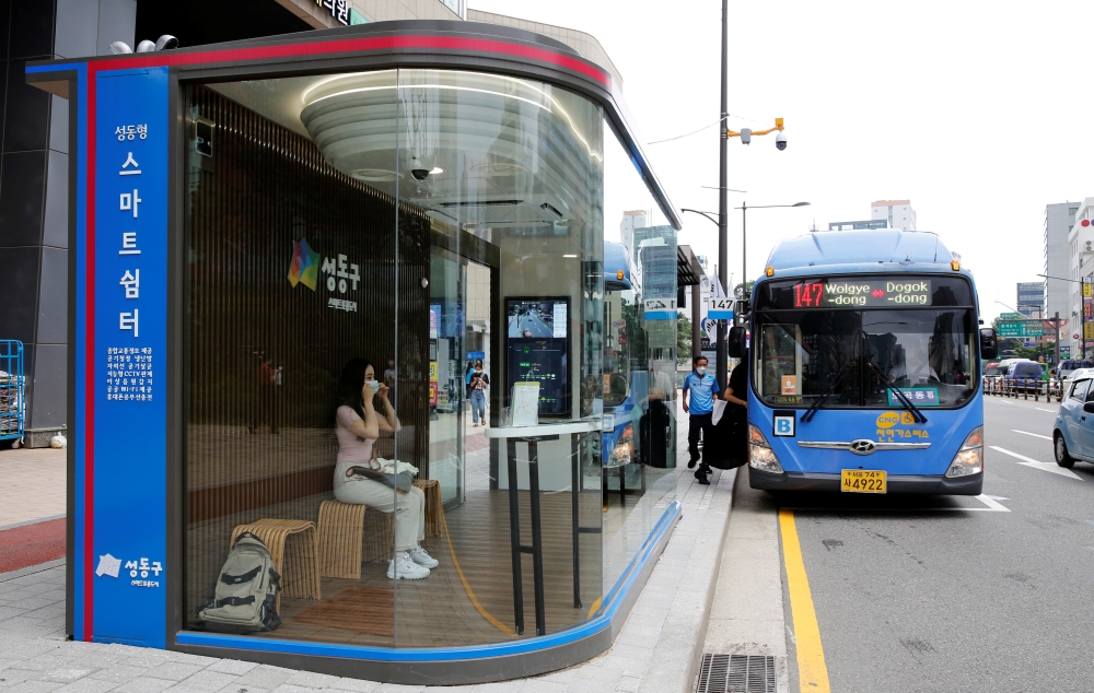 A woman wears a mask inside a glass-covered bus stop in which a thermal imaging camera, UV sterilizer, air conditioner, CCTV and digital signage are set, to avoid the spread of COVID-19 in Seoul, South Korea, August 14, 2020. REUTERS/Heo Ran