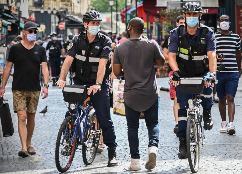 Paris municipal police officers wearing face masks ask people to put on their masks in Montorgueil street in Paris, on August 15, 2020. (AFP / BERTRAND GUAY)