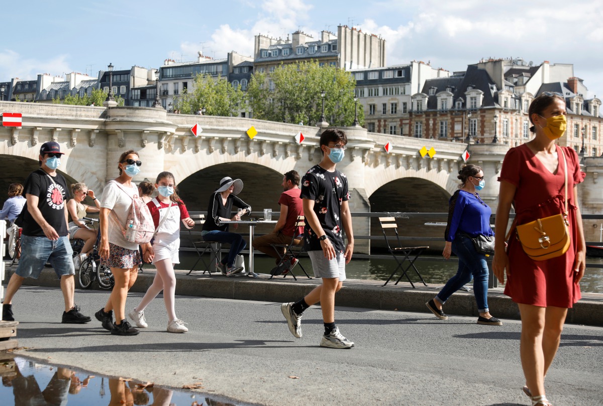 Pedestrians wearing protective face masks walk along the Seine river banks, as France reinforces mask-wearing as part of efforts to curb a resurgence of the coronavirus disease (COVID-19) across the country, Paris, France, August 15, 2020. REUTERS/Charles