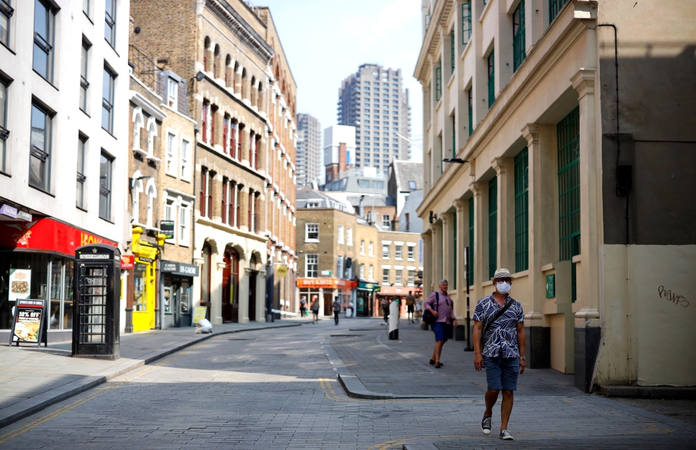 Pedestrians, some wearing a face mask or covering due to the COVID-19 pandemic, walk along a quite shopping street in London on August 12, 2020. AFP / Tolga Akmen