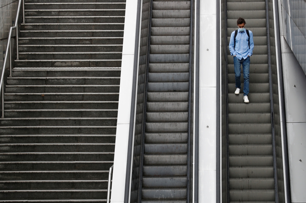 A man wearing a protective mask rides an escalator at the financial and business district of La Defense as France reinforces mask-wearing in public places as part of efforts to curb a resurgence of the coronavirus disease (COVID-19) across the country, ne