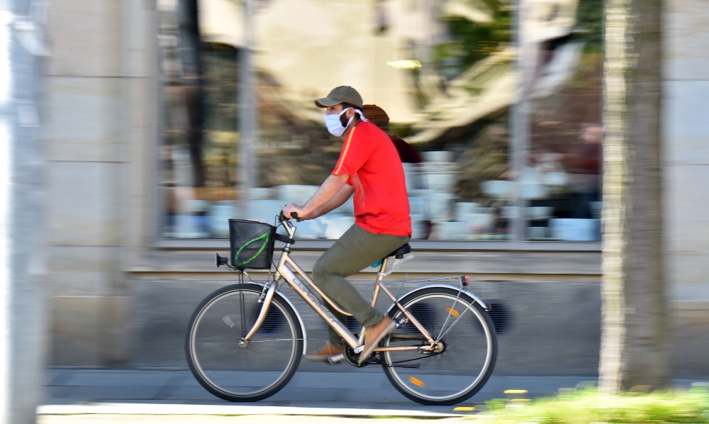 A man on a bicycle is wearing a protective mask in Dresden, Germany, April 20, 2020. REUTERS/Matthias Rietschel/File Photo