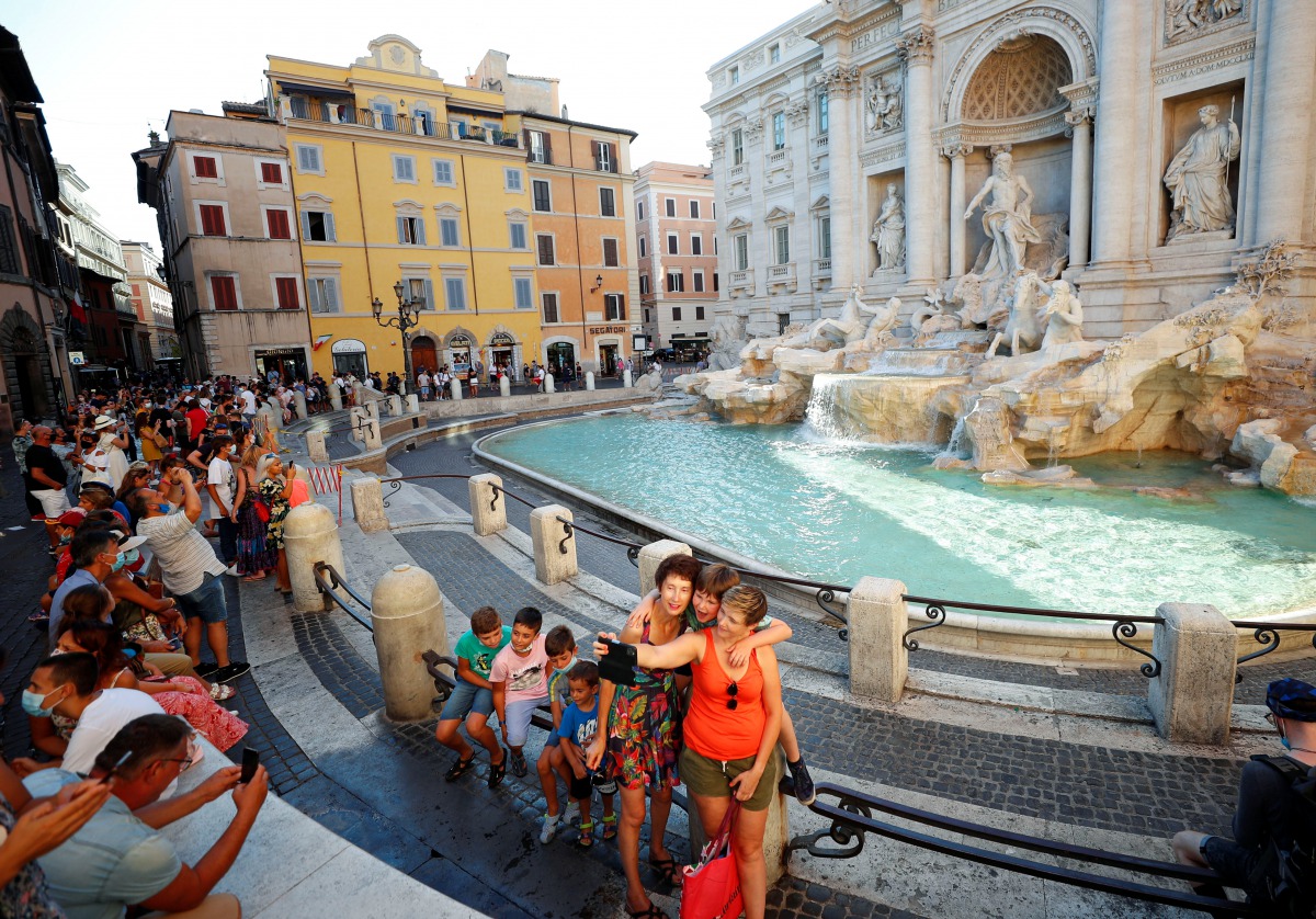People not wearing face masks take selfies in front of the Trevi Fountain following a government decree that states face coverings must be worn between 6 p.m. and 6 a.m. near bars and pubs and in areas where gatherings are more likely, due to the coronavi