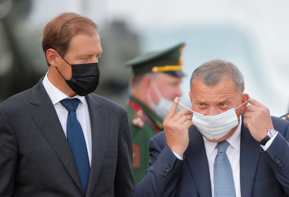 Russia's Deputy Prime Minister Yuri Borisov puts on his face mask as he stands next to Industry and Trade Minister Denis Manturov before the opening ceremony of the International military-technical forum 