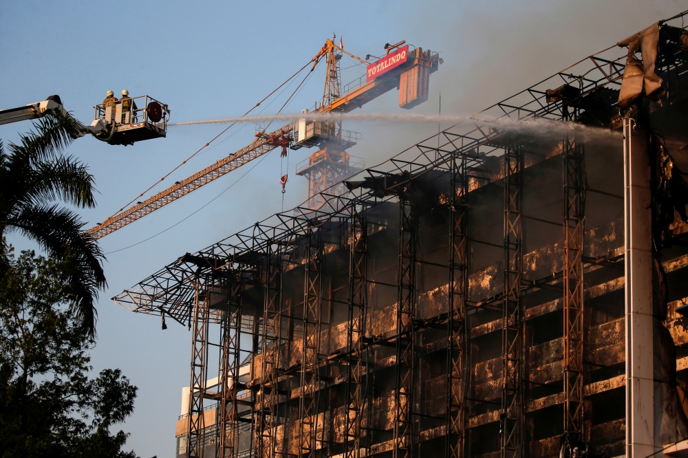 Firefighters stand on a crane as they spray water to extinguish fire at the Attorney's General office in Jakarta, Indonesia, August 23, 2020. REUTERS/Willy Kurniawan