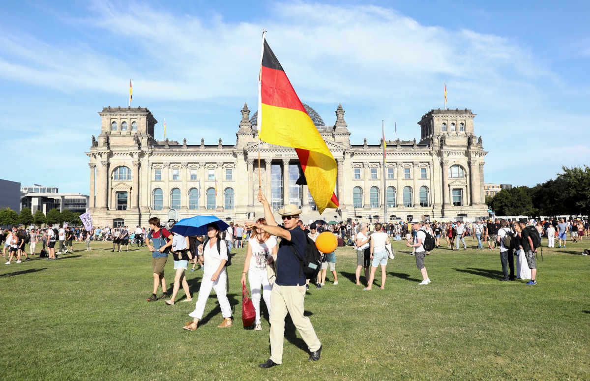 FILE PHOTO: A demonstrator holds a German flag near the Reichstag during a protest against the government's restrictions imposed over the coronavirus outbreak, in Berlin, Germany, August 1, 2020. REUTERS/Christian Mang/File Photo
