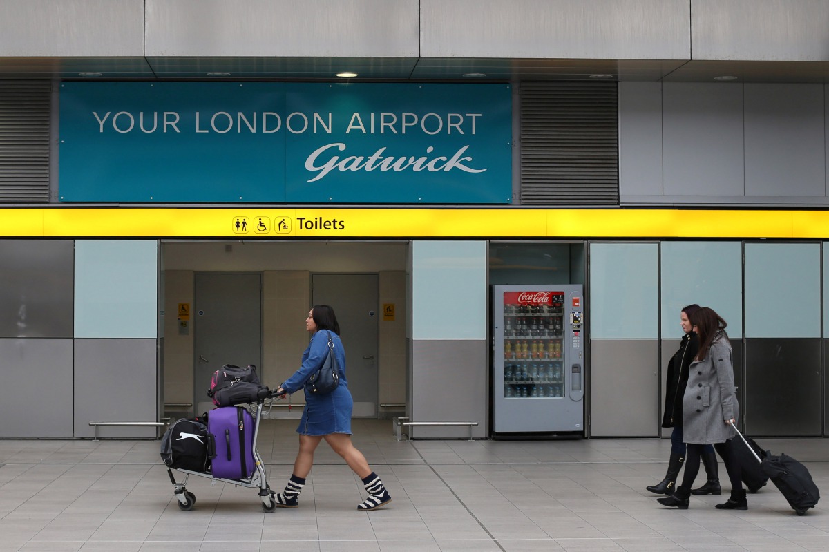FILE PHOTO: Travellers pass a sign for Gatwick Airport in southern Britain, December 17, 2015. REUTERS/Neil Hall/File Photo/File Photo
