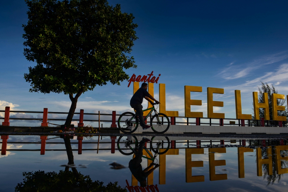 A man rides his bicycle during sunrise at Ulee Lheue beach in Banda Aceh on August 30, 2020. / AFP / CHAIDEER MAHYUDDIN