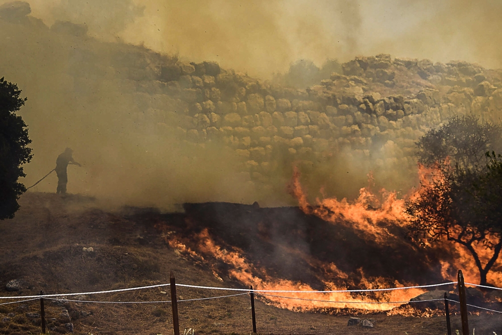A firefighter works to put out a wildfire near the archaeological site of Mycenae in the northeastern Peloponnese, on August 30, 2020. A wildfire broke out near the ruins of the Bronze Age stronghold of Mycenae in Greece on August 30, prompting the evacua