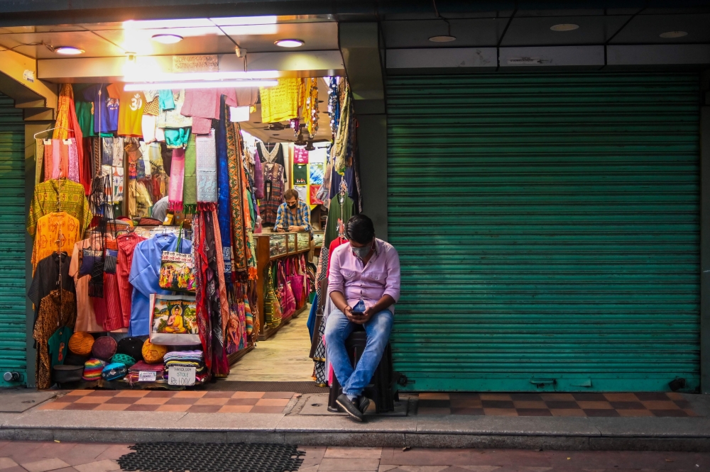 A man waits for customers at his clothing store in New Delhi on August 31, 2020. / AFP / Jewel SAMAD