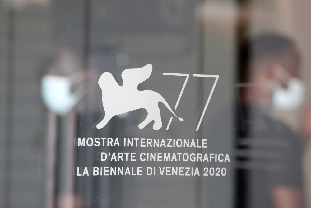 Workers wearing protective face masks are seen through the doors of Palazzo del Casino, ahead of the 77th Venice Film Festival, the first major international film festival held since the coronavirus disease (COVID-19) outbreak, in Venice, Italy, September