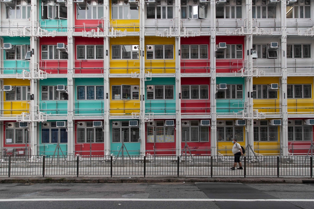 A man wearing a face mask as a precautionary measure against COVID-19 coronavirus waks past walks past a housing building in Hong Kong on August 29, 2020.  / AFP / May James / May JAMES