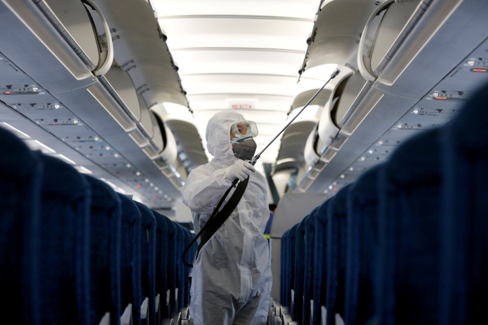 A health worker sprays disinfectant inside a Vietnam Airlines airplane to protect from the recent coronavirus outbreak, at Noi Bai airport in Hanoi, Vietnam February 21, 2020. REUTERS/Kham/File Photo