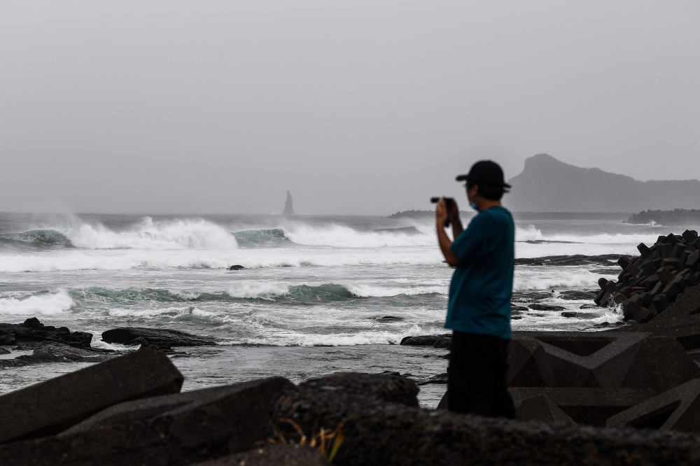 A man takes pictures along the coast as Typhoon Haishen approaches in Makurazaki, Kagoshima prefecture on September 6, 2020. / AFP / CHARLY TRIBALLEAU