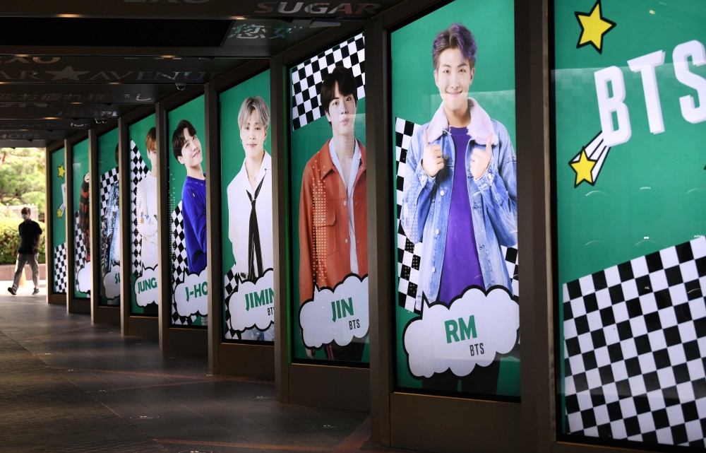 A man walks past commercial posters showing K-pop group BTS members outside a duty free shop in Seoul on September 1, 2020. AFP / Jung Yeon-je
 