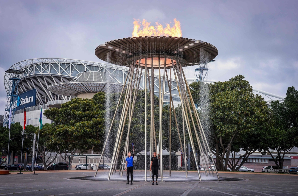 Young Australian athletes Tamsin Colley (L) and Tenayah Logan stand underneath the Sydney 2000 Olympic Games cauldron after it was relit during an event to mark the 20th anniversary of the opening ceremony at Cathy Freeman Park in the Olympic Boulevard in