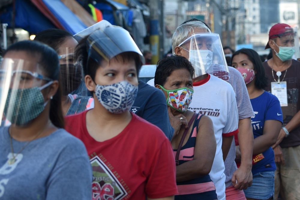 In this photo taken on September 19, 2020, people wearing face shields queue up at a public market in Manila. Many face the new normal in the Philippines, where it is now compulsory to wear both face masks and plastic shields in indoor public spaces and o
