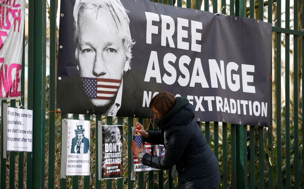 FILE PHOTO: A supporter of WikiLeaks founder Julian Assange posts a sign on the Woolwich Crown Court fence, ahead of a hearing to decide whether Assange should be extradited to the United States, in London, Britain February 25, 2020. REUTERS/Henry Nicholl