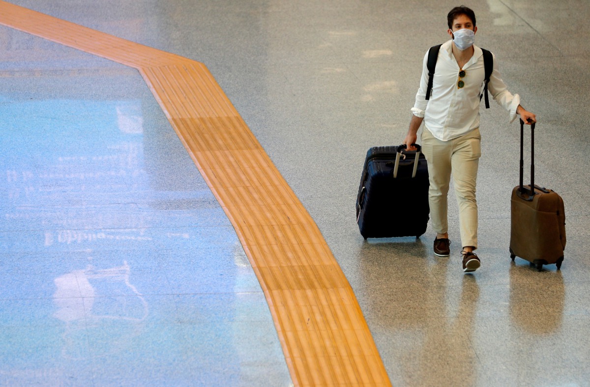FILE PHOTO: A passenger wearing a protective face mask walks at Fiumicino Airport In Rome, Italy, May 28, 2020.REUTERS / Guglielmo Mangiapane / File Photo

