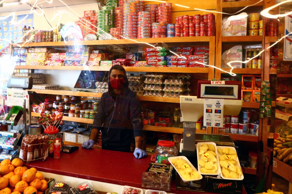 An employee wearing a face mask waits for customers behind a plastic curtain in a food shop at the Vallecas neighbourhood, amid the coronavirus disease (COVID 19) outbreak in Madrid, Spain, September 25, 2020. Reuters/Sergio Perez