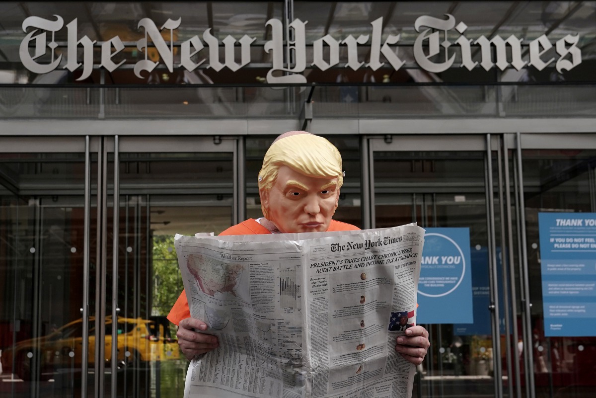 Mike Hisey dressed as U.S. President Donald Trump in a prison jumpsuit reads the New York Times in front of the New York Times office in the Manhattan borough of New York City, New York, U.S., September 28, 2020. REUTERS/Carlo Allegri
