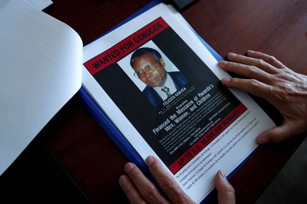 FILE PHOTO: Eric Emeraux, head of the Gendarmerie's Central Office for Combating Crimes Against Humanity, Genocides and War Crimes (OCLCH), displays documents with a wanted poster depicting a photograph of Felicien Kabuga during an interview with Reuters 