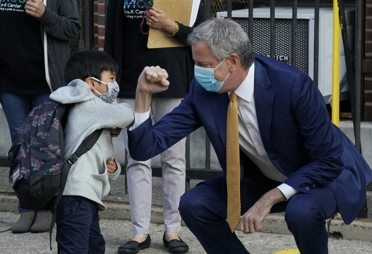 (FILES) In this file photo New York City Mayor Bill de Blasio does a social distancing elbow bump with four-year old Oliver as he welcomes students to Pre-K at Mosaic Pre-K Center in the Queens section of New York September 21, 2020. AFP / TIMOTHY A. CLAR