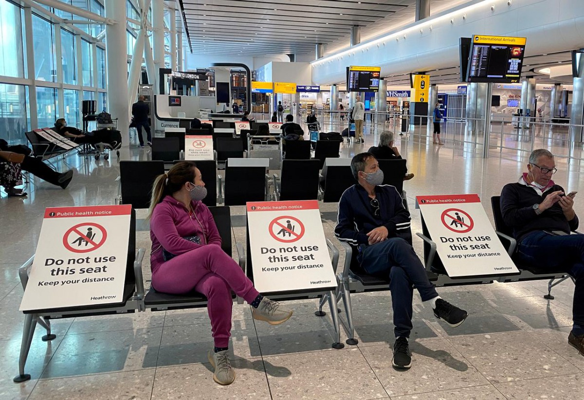 FILE PHOTO: People sit amongst socially-distanced seating signs at Heathrow Airport, as the spread of the coronavirus disease (COVID-19) continues, in London, Britain, May 10, 2020. REUTERS/Toby Melville/File Photo
