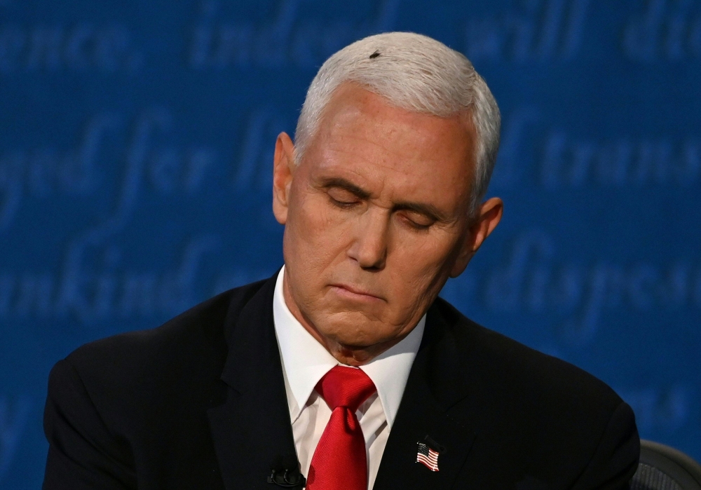  A fly rests on the head of US Vice President Mike Pence as he takes notes during the vice presidential debate against US Democratic vice presidential nominee and Senator from California Kamala Harris in Kingsbury Hall at the University of Utah on October