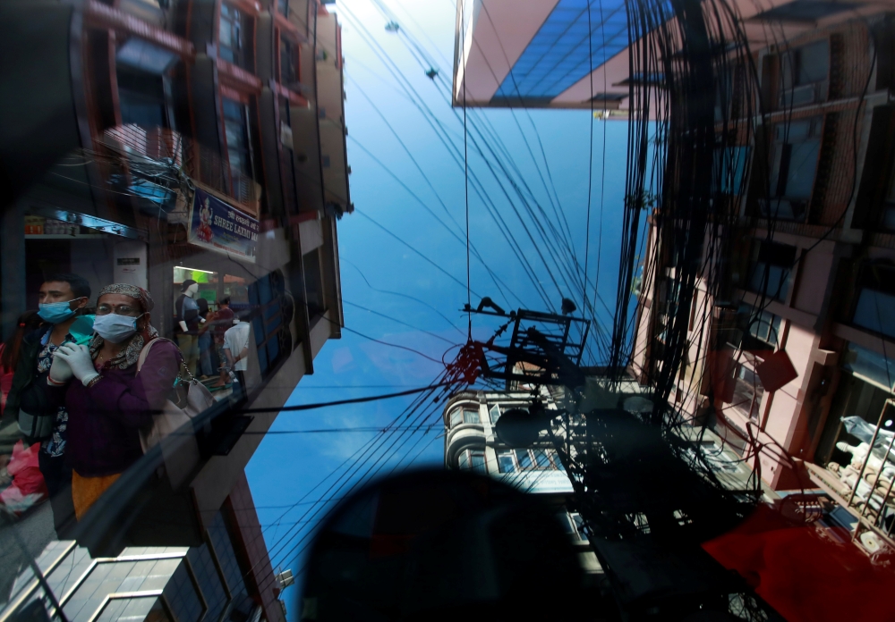 :People wearing protective face masks walk along a street as buildings are reflected on the windshield of a vehicle amid the outbreak of the coronavirus disease (COVID-19), in Kathmandu, Nepal October 8, 2020. REUTERS/Navesh Chitrakar

