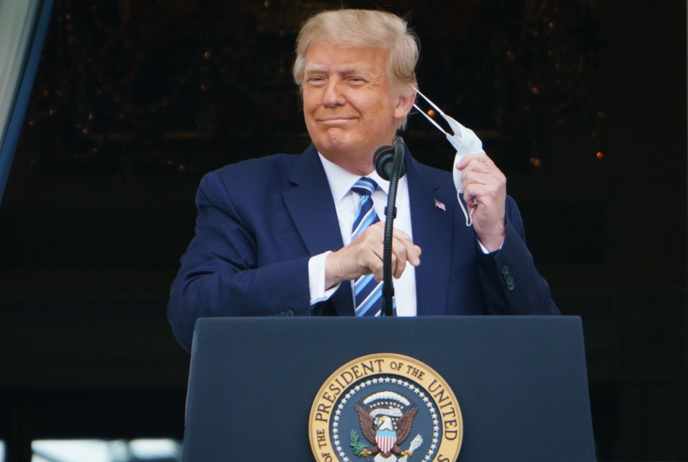 US President Donald Trump takes his mask off before speaking from the South Portico of the White House in Washington, DC during a rally.  AFP / MANDEL NGAN