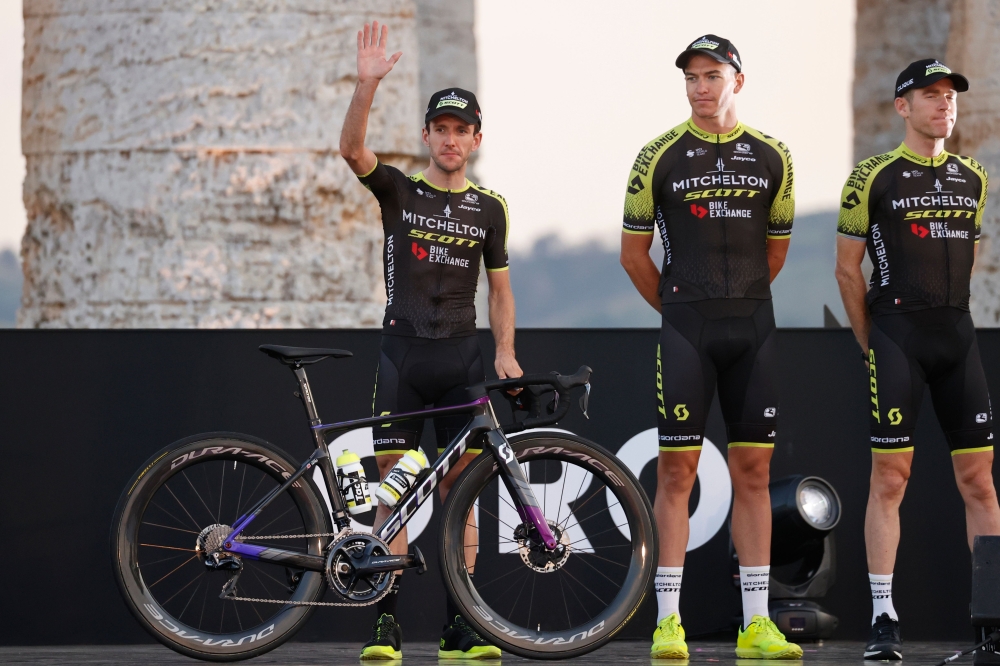 In this file photo taken on October 01, 2020 Team Mitchelton rider Great Britain's Simon Yates (L) waves on stage at the Doric Temple of Segesta, near Palermo, Sicily, during an opening ceremony of presentation of participating teams and riders, two days