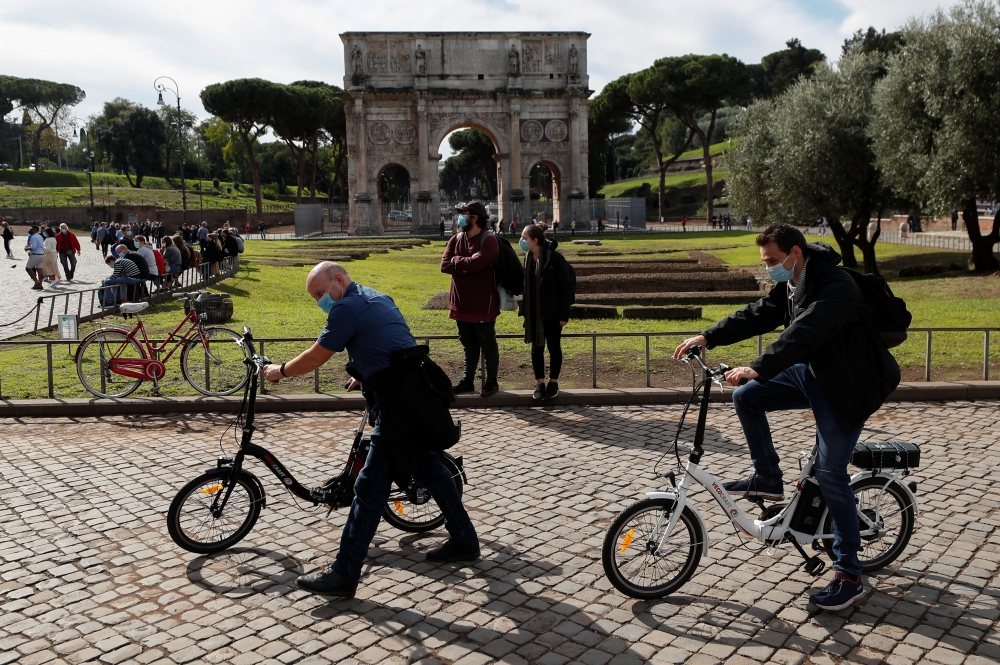 People wearing face masks are seen next to the Arch of Constantine as Italy adopts new restrictions aimed at curbing a surge in the coronavirus disease (COVID-19) infections, in Rome, Italy October 13, 2020. REUTERS/Guglielmo Mangiapane