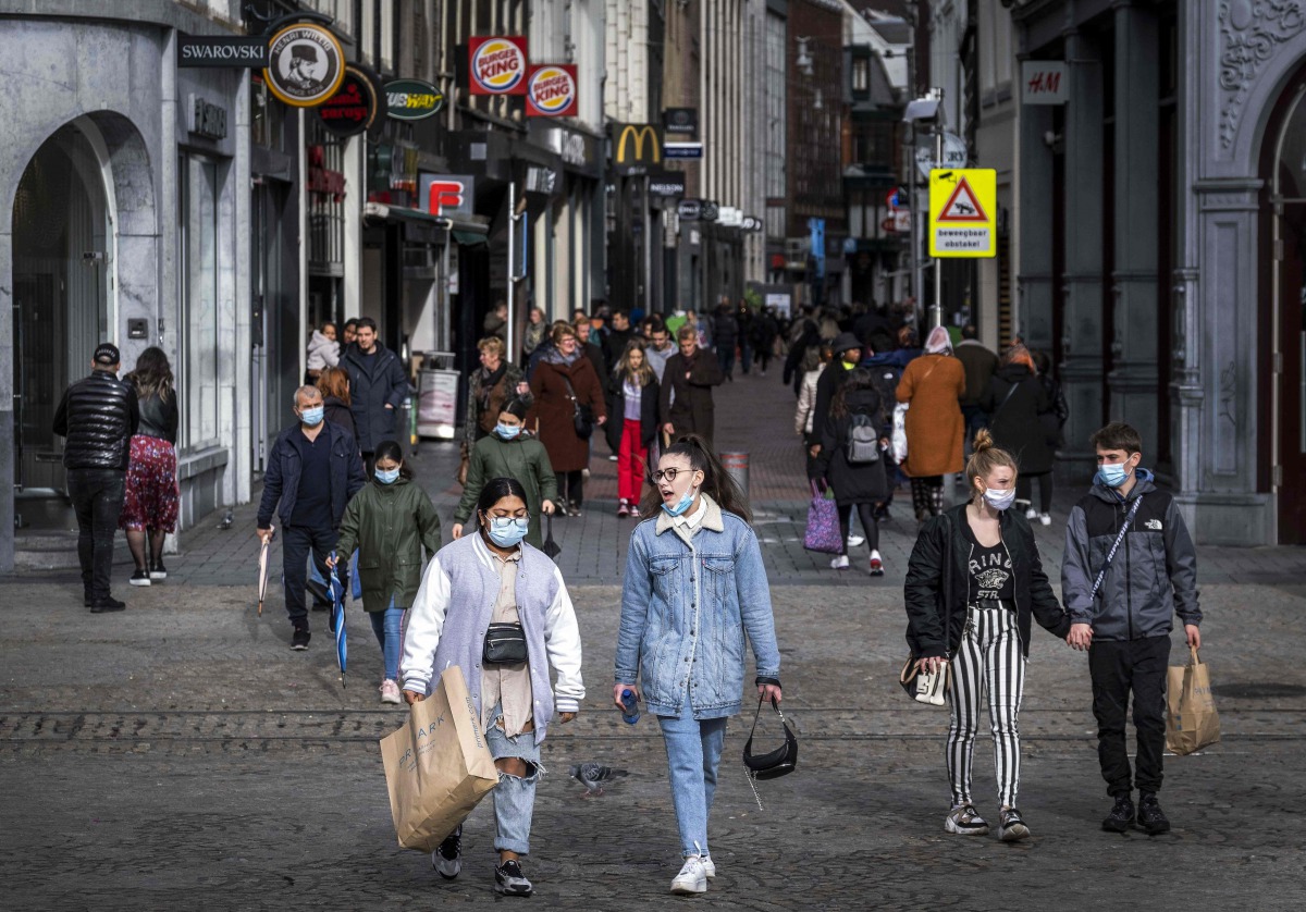 People wearing face masks walk on a shopping street in the center of Amsterdam on October 11, 2020. The Dutch government is expected to take new measures to halt the spread the Covid-19 disease caused by the novel coronavirus. - / AFP / ANP / Ramon van Fl