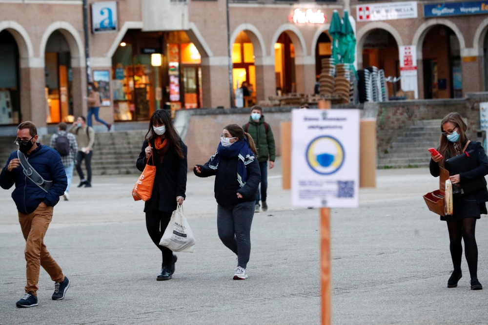 People wearing protective masks walk in an area of mandatory mask use, ahead of a curfew imposed by local authorities in the university town of Louvain-La-Neuve amid the coronavirus disease (COVID-19) outbreak, in Belgium, October 13, 2020. REUTERS/Franco