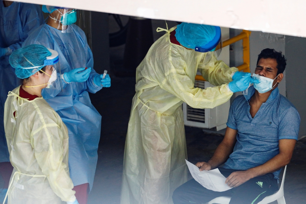A migrant worker undergoes a nose swab test as medical workers look on at a dormitory amid the coronavirus disease (COVID-19) outbreak in Singapore, April 28, 2020. REUTERS/Edgar Su/File Photo