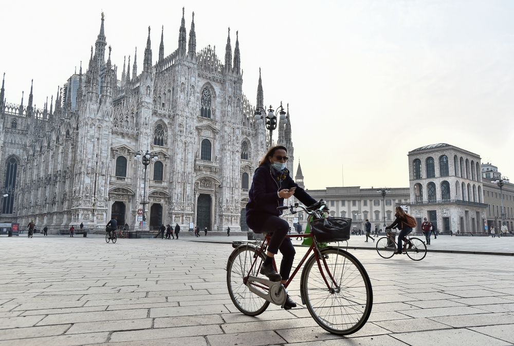 A person wearing a protective mask rides a bicycle at Duomo Square, in the northern Lombardy region of Italy, after the government brings in new restrictive measures due to a rise in the number of the coronavirus disease (COVID-19) infections, in Milan, I
