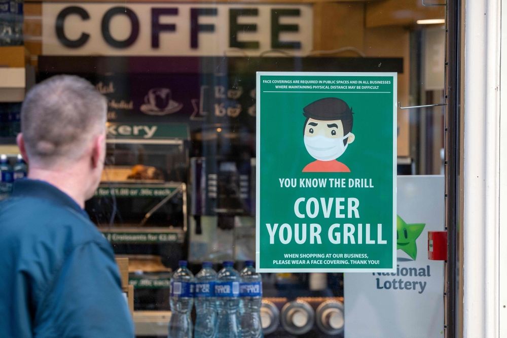 An information poster advising the wearing of face coverings as a precaution against the spread of the novel coronavirus covid-19 is seen on the window of a coffee shop in Dublin on October 21, 2020 as Ireland prepares to enter a second national lockdown 