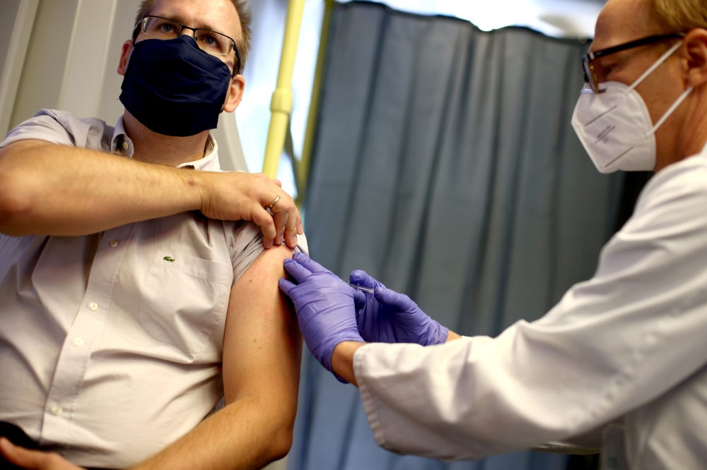 FILE PHOTO: A healthcare worker of the free influenza vaccination programme vaccinates a citizen against the flu inside a tram, as the global spread of the the coronavirus disease (COVID-19) continues, in Vienna, Austria, October 1, 2020. REUTERS/Lisi Nie